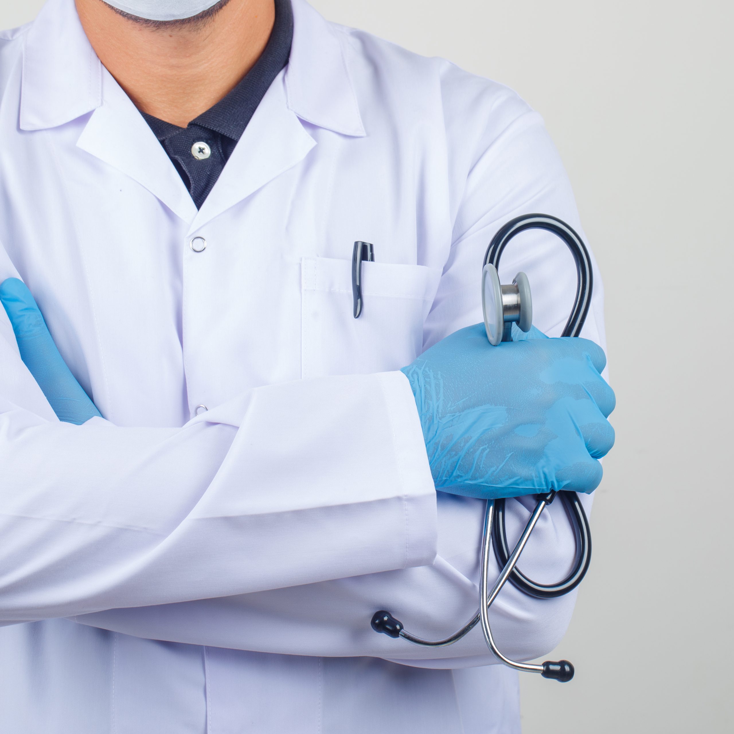 Doctor crossing arms while holding stethoscope in white coat front view.